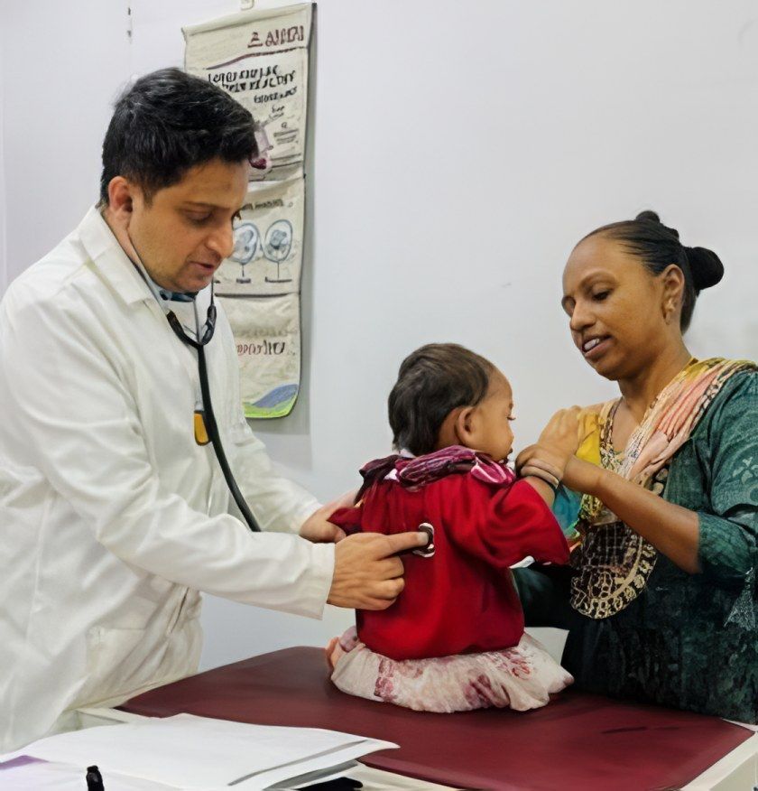 Dr. Sunildatt listens to a baby girl’s chest as her mother holds her